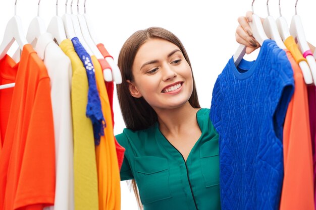 clothing, fashion, style and people concept - happy woman choosing clothes at home wardrobe