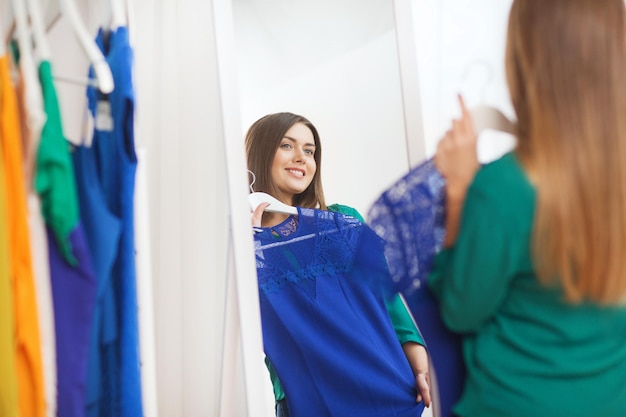 clothing, fashion, style and people concept - happy woman choosing clothes at home wardrobe