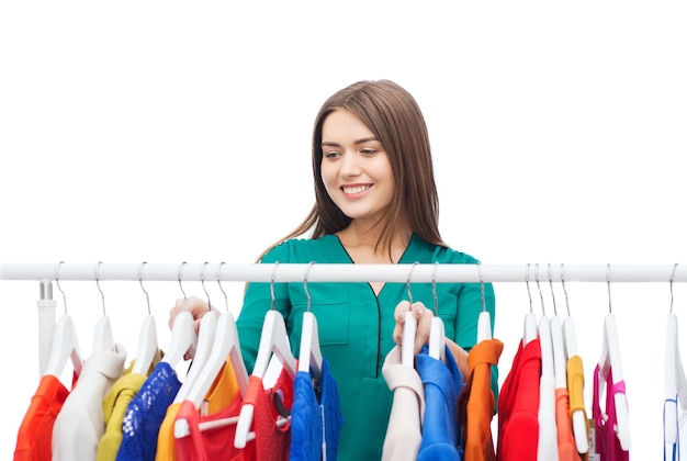 clothing, fashion, style and people concept - happy woman choosing clothes at home wardrobe