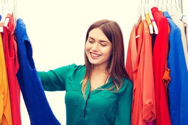 clothing, fashion, style and people concept - happy woman choosing clothes at home wardrobe