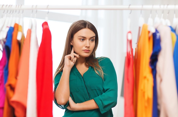 clothing, fashion, style and people concept - woman choosing clothes at home wardrobe