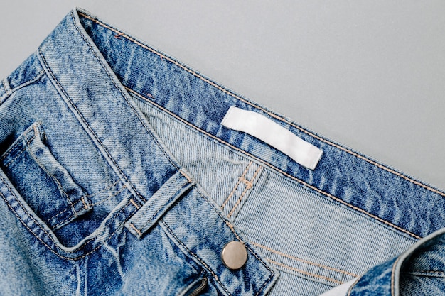 Etichetta di abbigliamento all'interno dei jeans su sfondo grigio. modello
