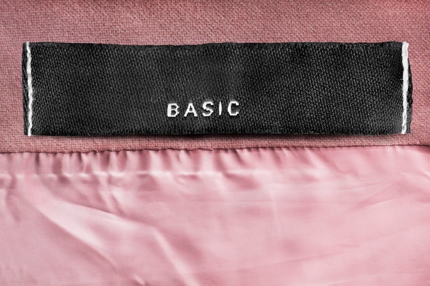 Clothing label says basic on pink fabric background