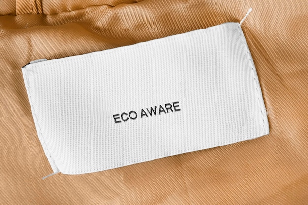 Clothing label says eco aware on yellow fabric background