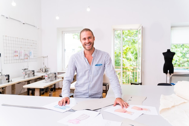 Stilista di abbigliamento che crea un nuovo design per un vestito - stilista che lavora su un marchio di abbigliamento in una fabbrica tessile