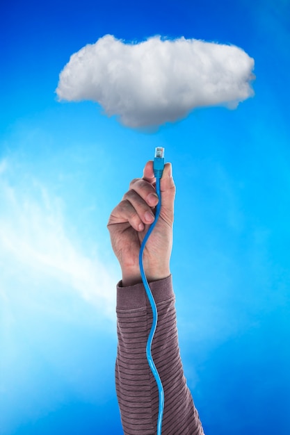 Cloud and hand with cable over blue