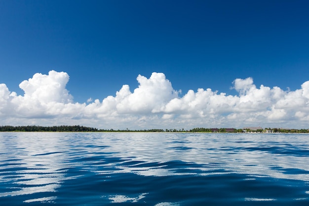 Clouds on blue sky over calm sea with sunlight reflection