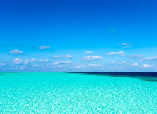 日光の反射と穏やかな海の上の青い空の雲