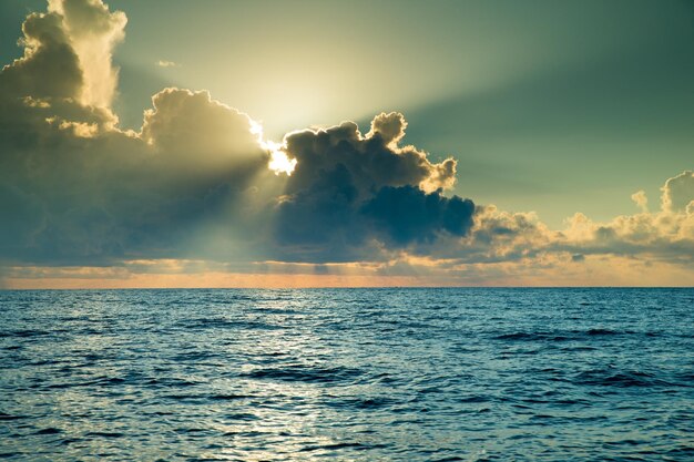 Clouds on blue sky over calm sea with sunlight reflection