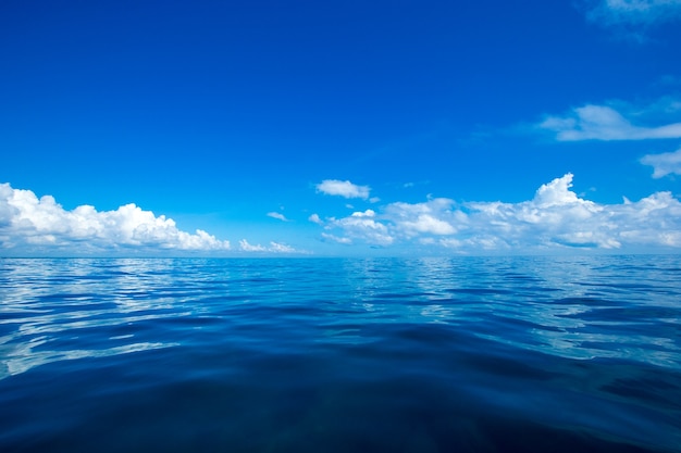 日光の反射と穏やかな海の上の青い空の雲