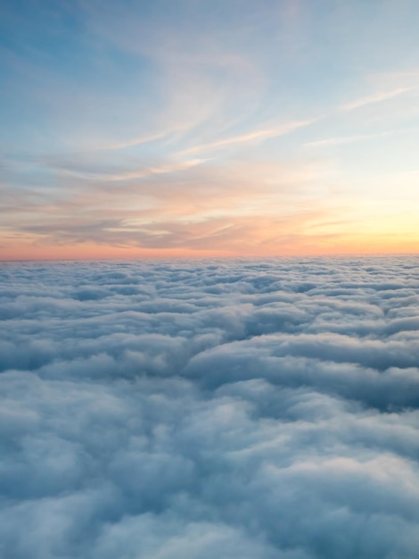 自然な夕暮れの光の下で航空機の窓からの雲の上