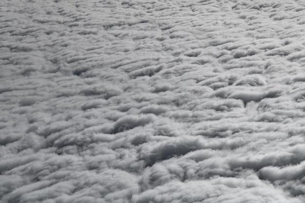 Clouds high in the sky, white and grey fluffy clouds from airplane window view