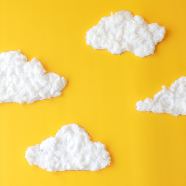 Clouds made of cotton on yellow background Space for text Mock up for beauty or cosmetic products