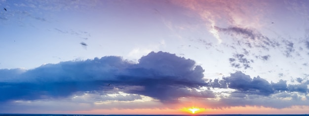 空の雲、夜明けまたは日没、パノラマ。明るいオレンジ色の日光が夕方の空を照らします。