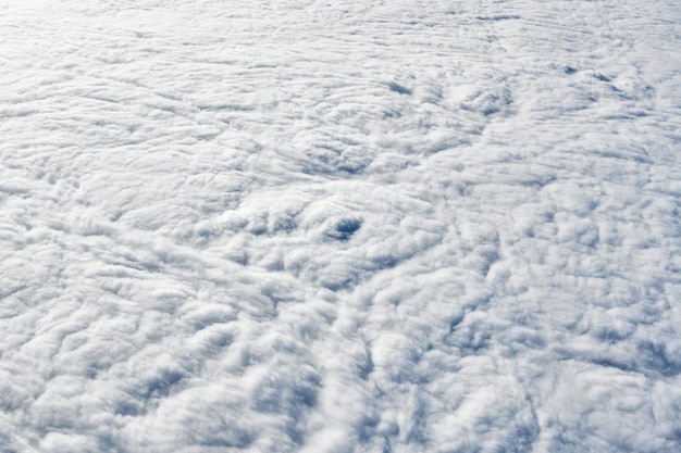 Over clouds top view from aircraft window thick white blue clouds looks like soft foam