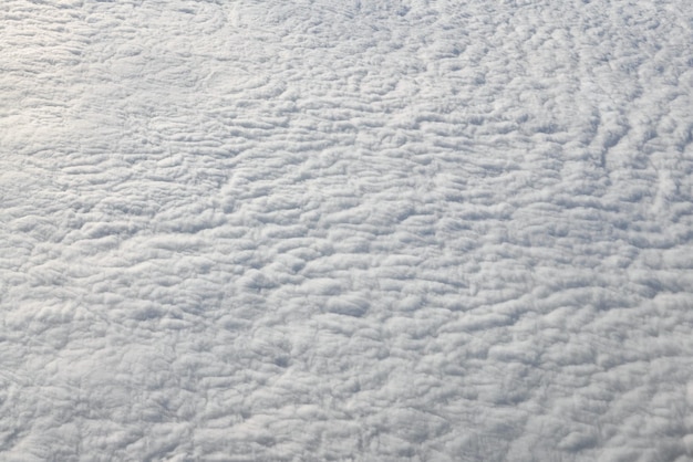 Over clouds top view from aircraft window thick white blue clouds looks like soft foam