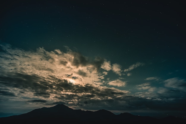 山の風景の上に月明かりのある雲