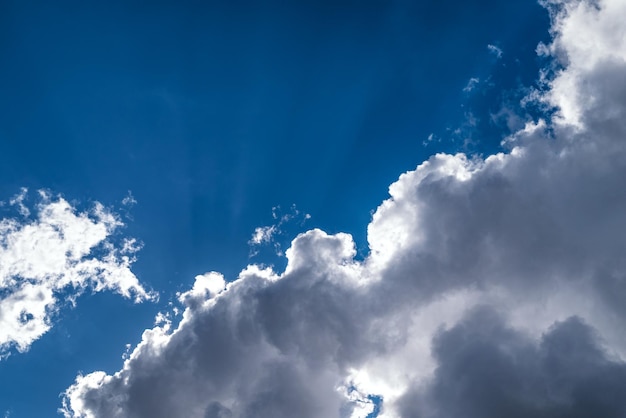 Cloudscape of large white and grey cumulus clouds in the bright blue sky