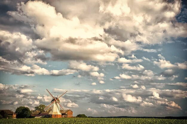 Cloudscape met windmolen en boerderijlandbouw Molen en huisjes op groen veld landbouw Landelijk landschap op bewolkte blauwe hemelvakantie Zomervakantie op het platteland