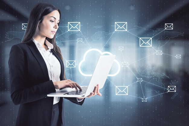Cloudtechnologie en opslagconcept met zakenvrouw die aan laptop werkt op digitale muurachtergrond met cloudteken in het midden van mailsymbolen