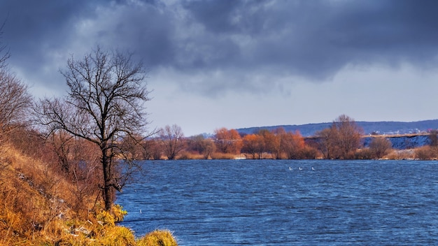 Cloudy autumn landscape. River and dark stormy sky before rain