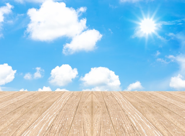 Cloudy blue sky with sun beam and wood floor