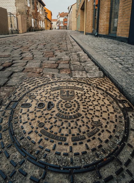 Cloudy day in the old part of Klaipeda Lithuania on a cobbled street with a beautiful sewer manhole