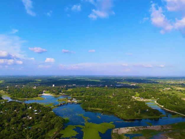 Cloudy shiny blue sky above the blue lake and green forest