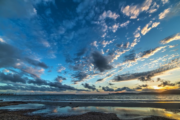 Cloudy sky over Alghero shore at sunset