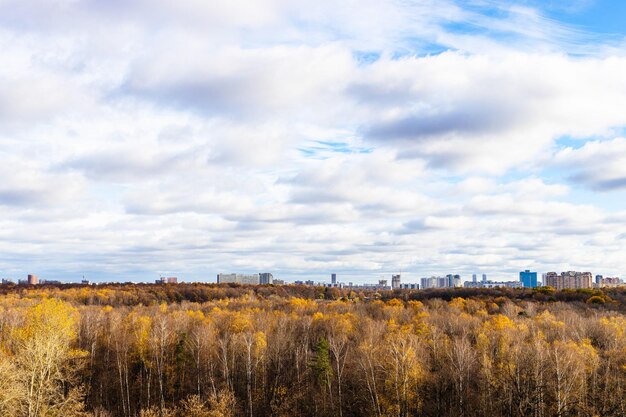 Облачное небо над лесом и городом осенью