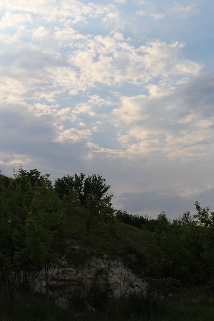 A cloudy sky over a hill with trees