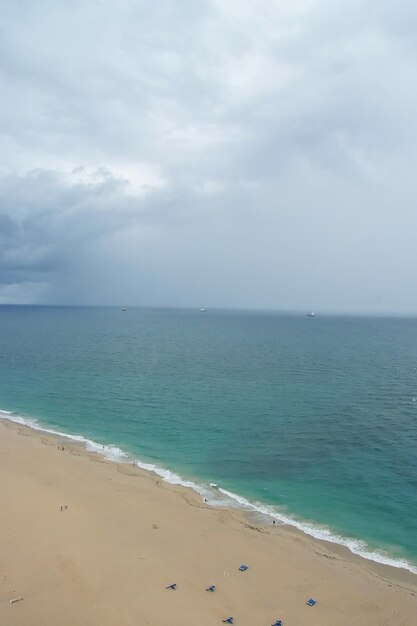 Cloudy skyline on sand beach and blue sea water on natural background in Fort Lauderdale, USA. Summer vacation and travelling concept. Tourism and tourist destination.