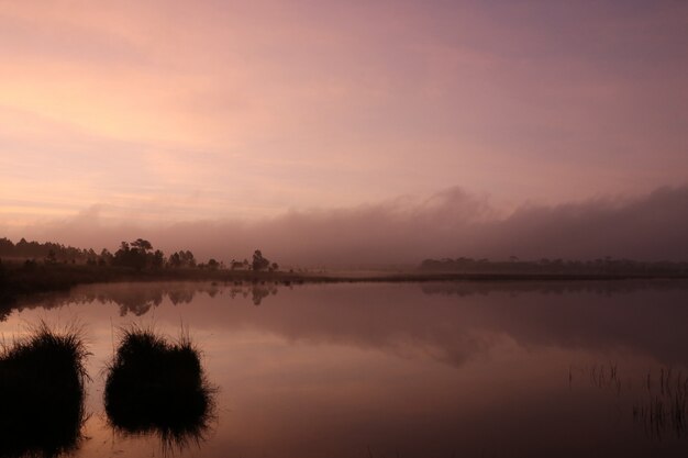 Cloudy and sunrise reflection on water surface with mist