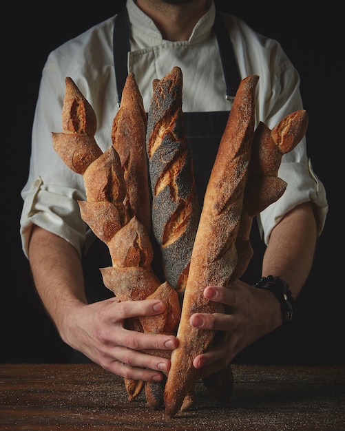 Clous up hands man holding baguettes on a wooden table