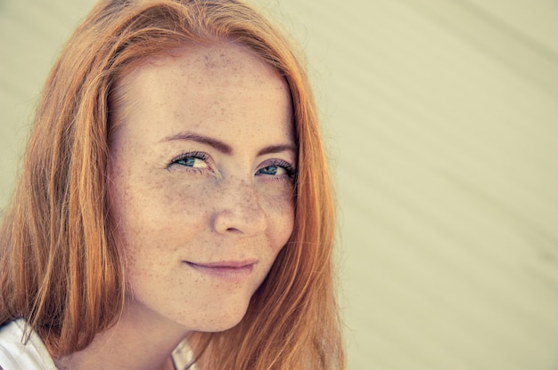 Clouse-up natural positive portrait of young gorgeous caucasian ginger girl with freckles outdoors. Healthy lifestyle, beauty, natural concept.