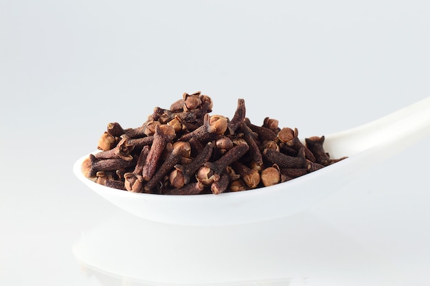 Clove in spoon isolated on a white background