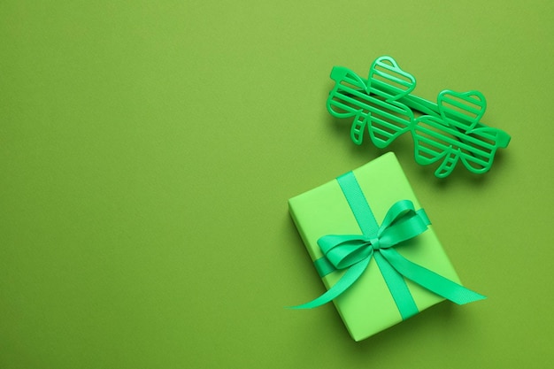 Clover glasses and gift box on green background