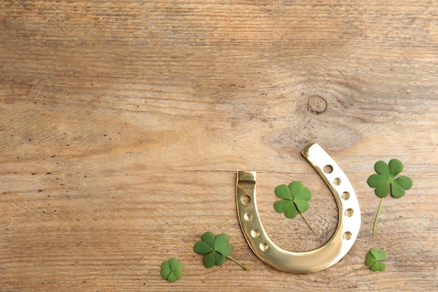 clover leaves and horseshoe on wooden table flat lay with space for text st patricks day celebration