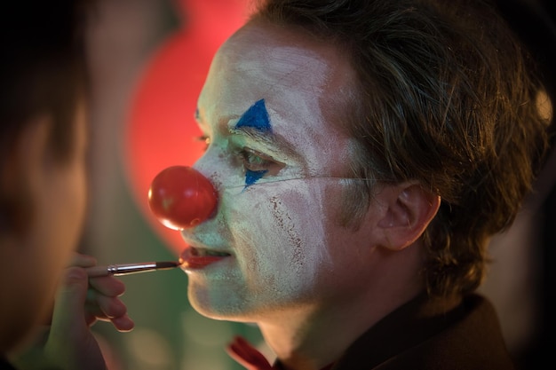 Clown concept makeup artist applying paint on the man clown