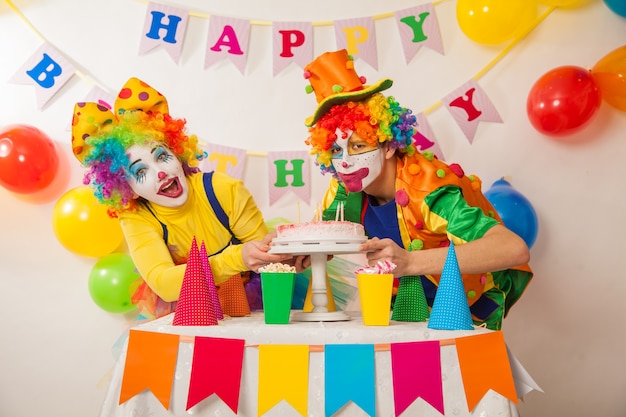 Una ragazza clown e un ragazzo clown in vacanza stanno litigando per una torta di compleanno