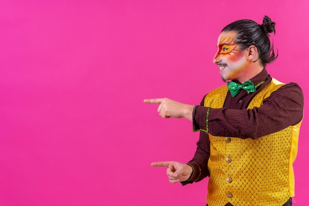 Clown with white facial makeup showing empty space from pink background announcing something pointing left