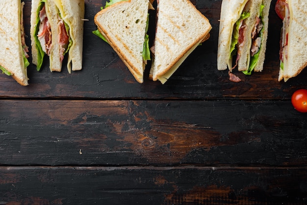 Club sandwich met vlees, kaas, tomaat, ham, op donkere houten tafel, bovenaanzicht