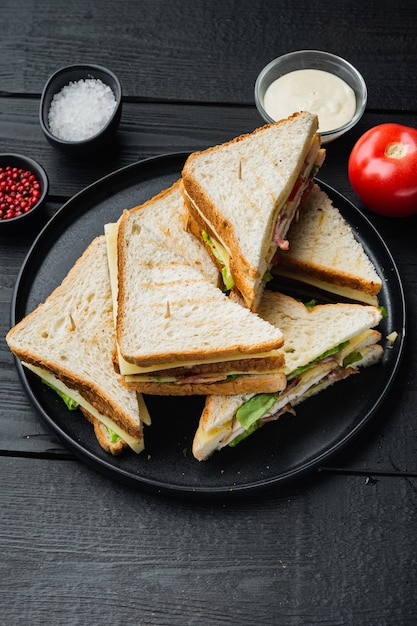 Club sandwich met vlees, kaas, tomaat, ham, op zwarte houten tafel