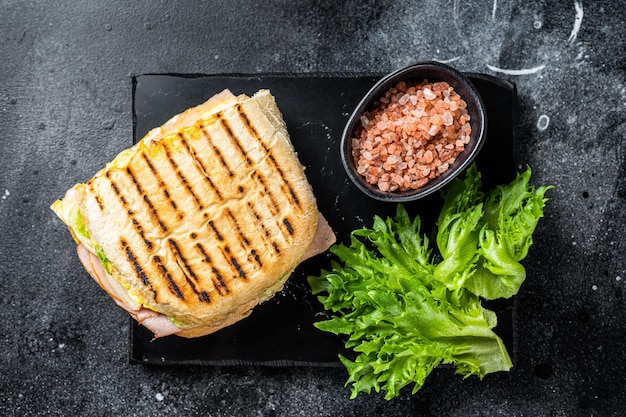 Club sandwich panini with ham tomato cheese and basil Black background top view