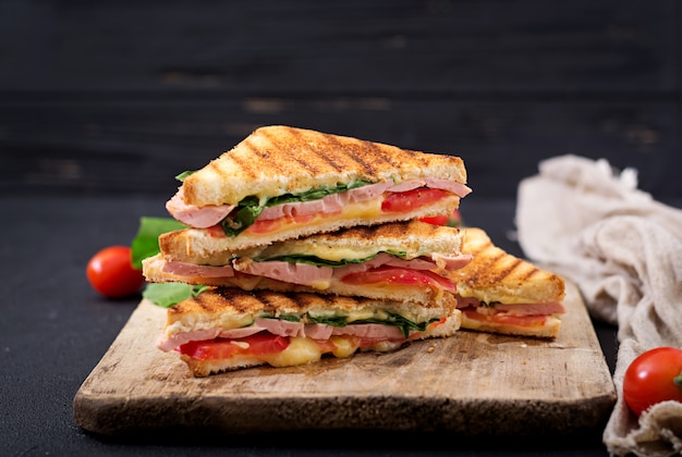 Club sandwich panini with ham, tomato, cheese and basil.