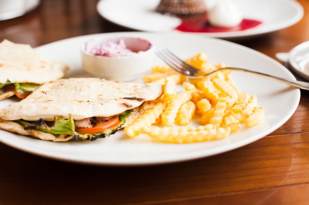 Club sandwich in pita with fried potato and salad