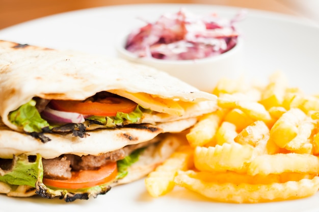 Club sandwich in pita with fried potato and salad