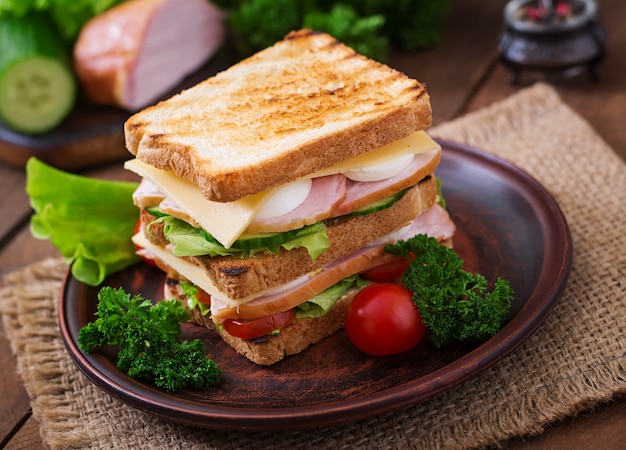 Club sandwich with cheese, cucumber, tomato, ham and eggs.