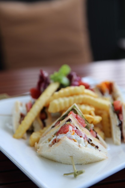 Club sandwich with chicken breast , bacon , tomato , cucumber and fried potatoes