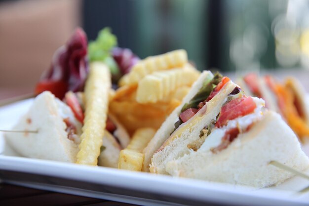 Club sandwich with chicken breast , bacon , tomato , cucumber and fried potatoes